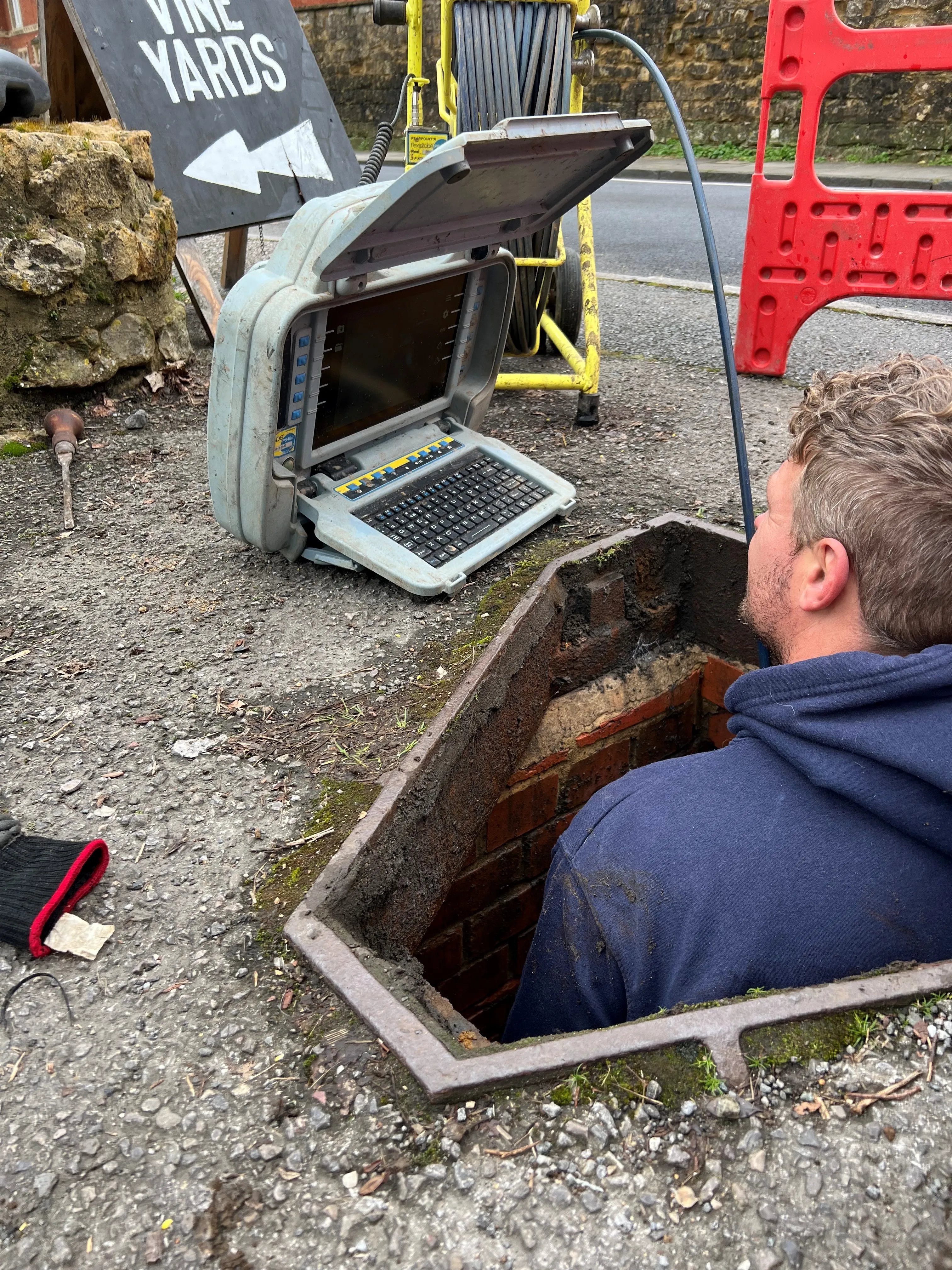 A man sitting in a hole with a laptop on his lap.