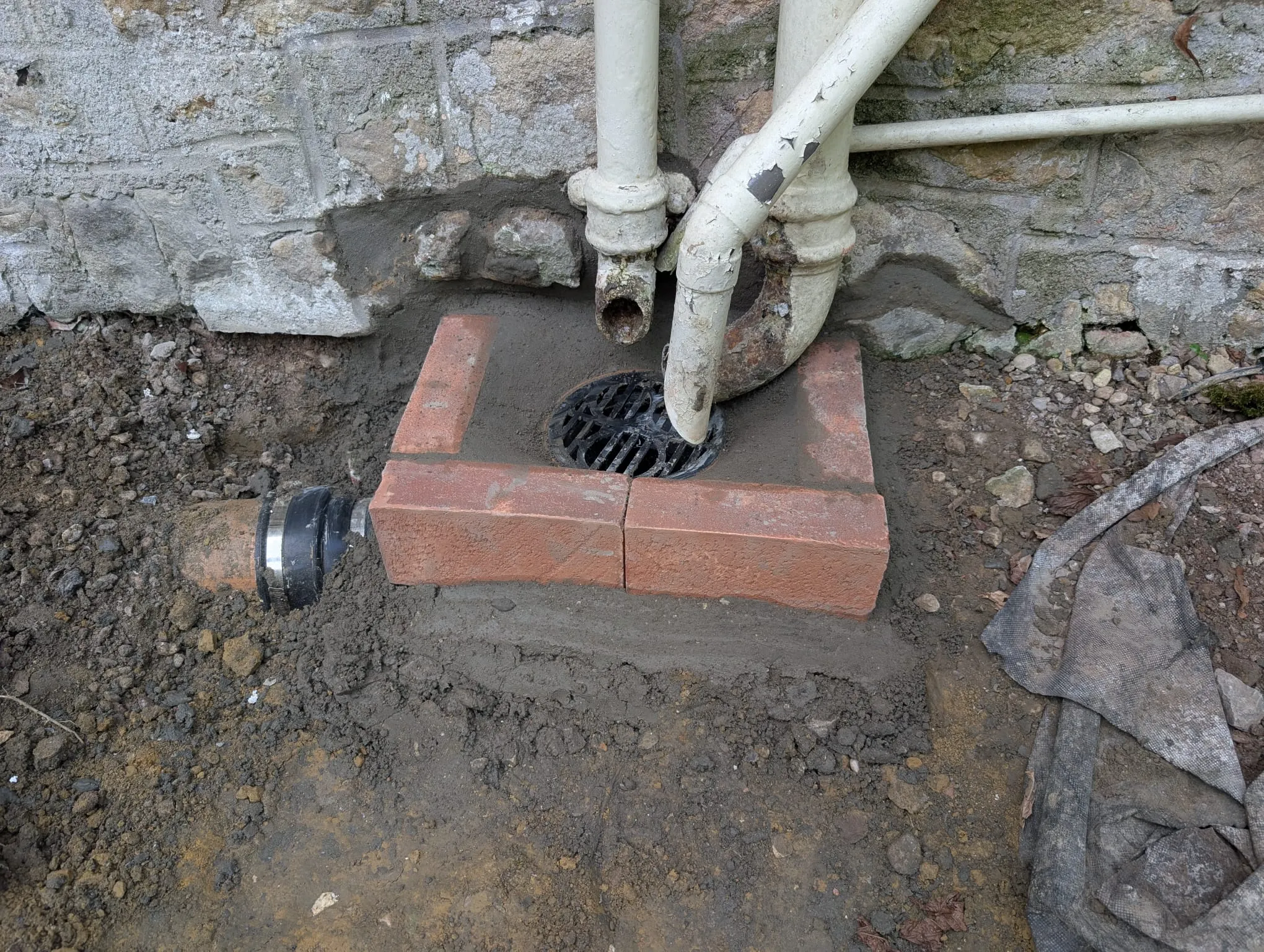 A drain in the ground next to a pipe.