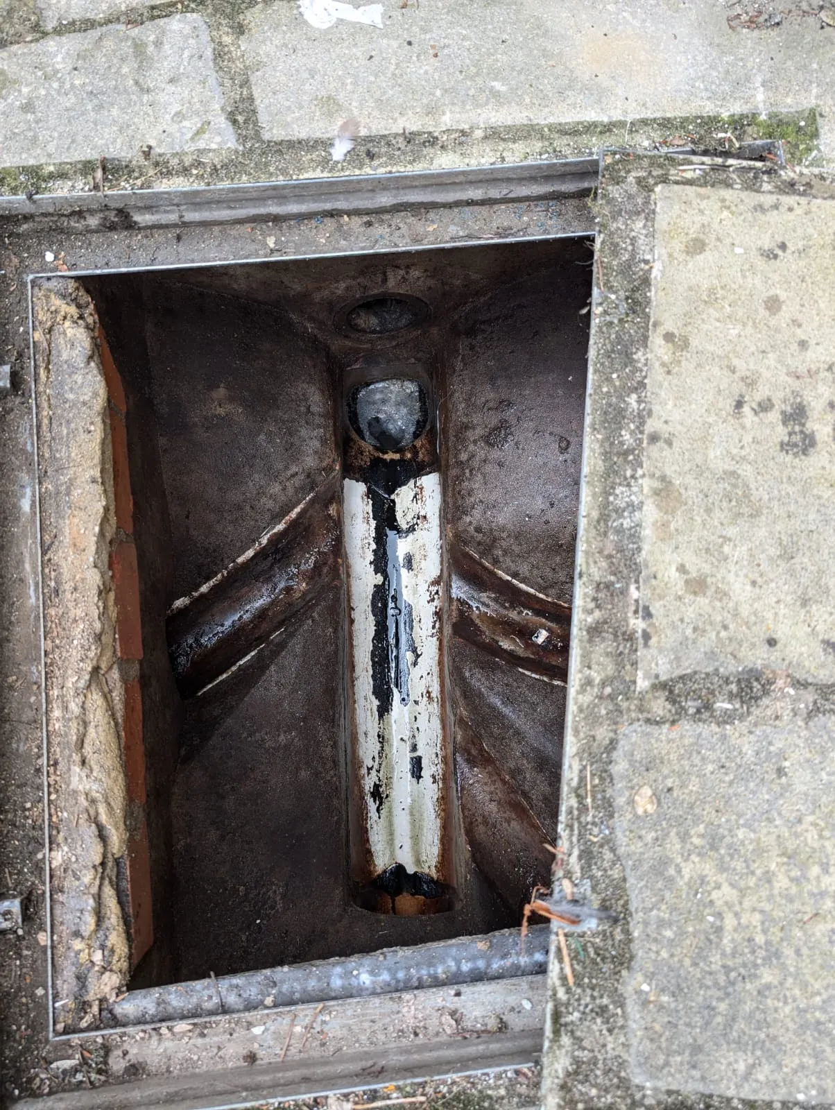A hole in the ground with a pipe in it.