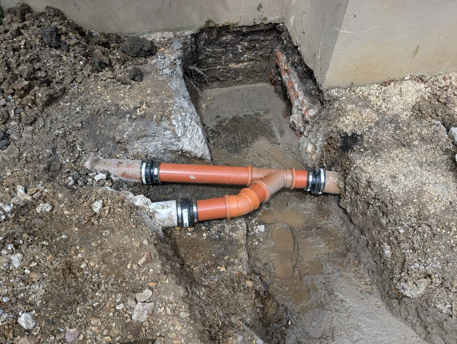 A pipe laying on the ground next to a wall.