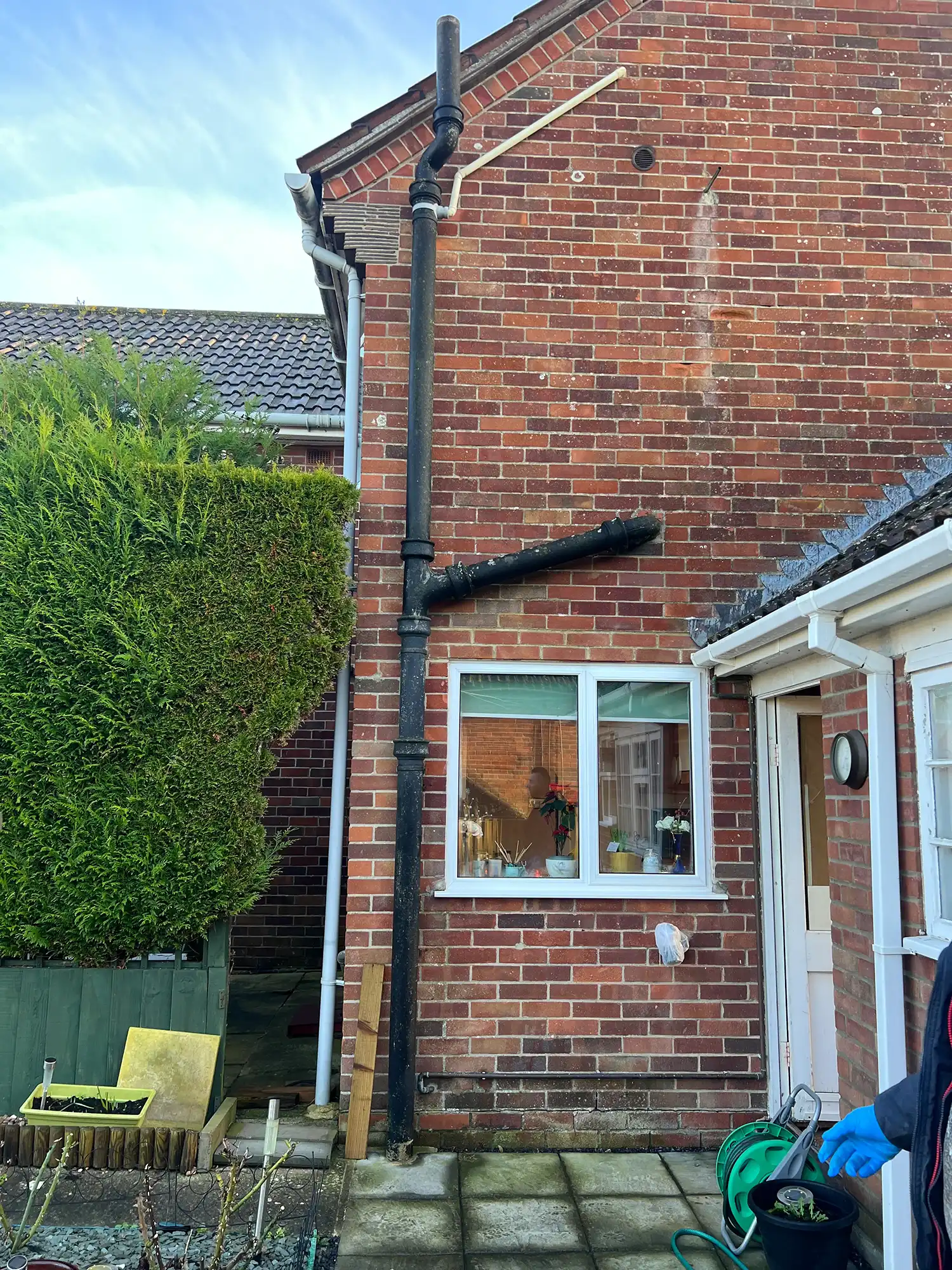 a man standing outside of a house with a hose